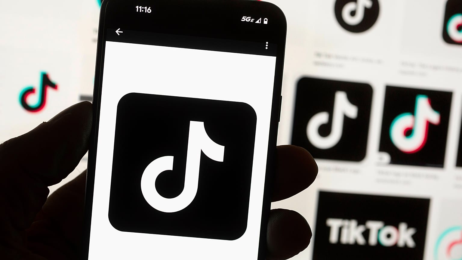 Das TikTok-Logo wird auf einem Mobiltelefon vor einem Computerbildschirm angezeigt, auf dem die TikTok-Homepage zu sehen ist, in Boston, 7. Mai 2024
