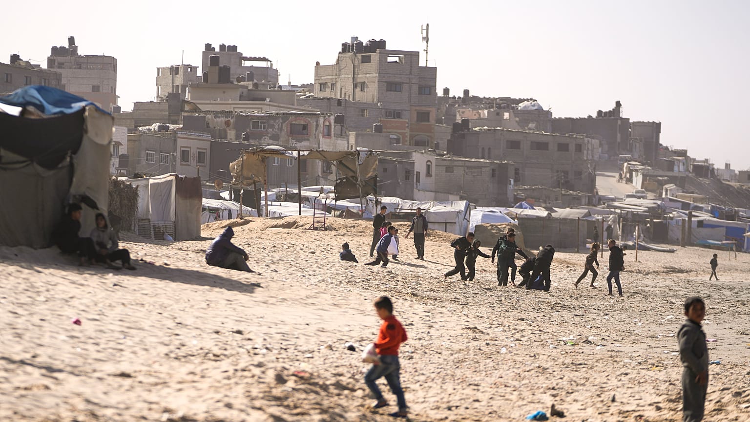 أطفال يلعبون على الرمال في مخيم للنازحين الفلسطينيين على شاطئ البحر في دير البلح، وسط قطاع غزة، الجمعة، 27 ديسمبر/كانون الأول 2024