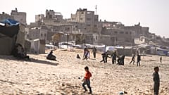أطفال يلعبون على الرمال في مخيم للنازحين الفلسطينيين على شاطئ البحر في دير البلح، وسط قطاع غزة، الجمعة، 27 ديسمبر/كانون الأول 2024
