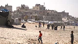 أطفال يلعبون على الرمال في مخيم للنازحين الفلسطينيين على شاطئ البحر في دير البلح، وسط قطاع غزة، الجمعة، 27 ديسمبر/كانون الأول 2024