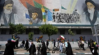 Иранские верующие проходят мимо фрески с изображением аятоллы Али Хаменеи (слева) после пятничной молитвы в Тегеране, 19 апреля 2024 года.