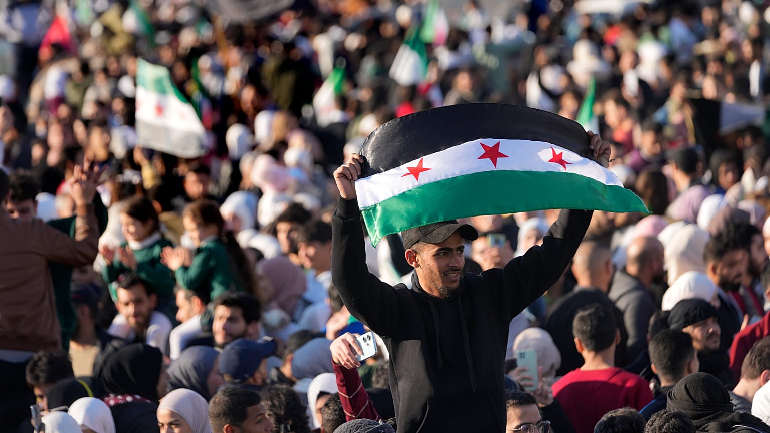 Un hombre sirio ondea una bandera revolucionaria durante una celebración en Damasco, 13 de diciembre de 2024.