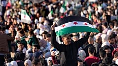 Ein syrischer Mann schwenkt eine Revolutionsflagge während einer Feier in Damaskus, 13. Dezember 2024