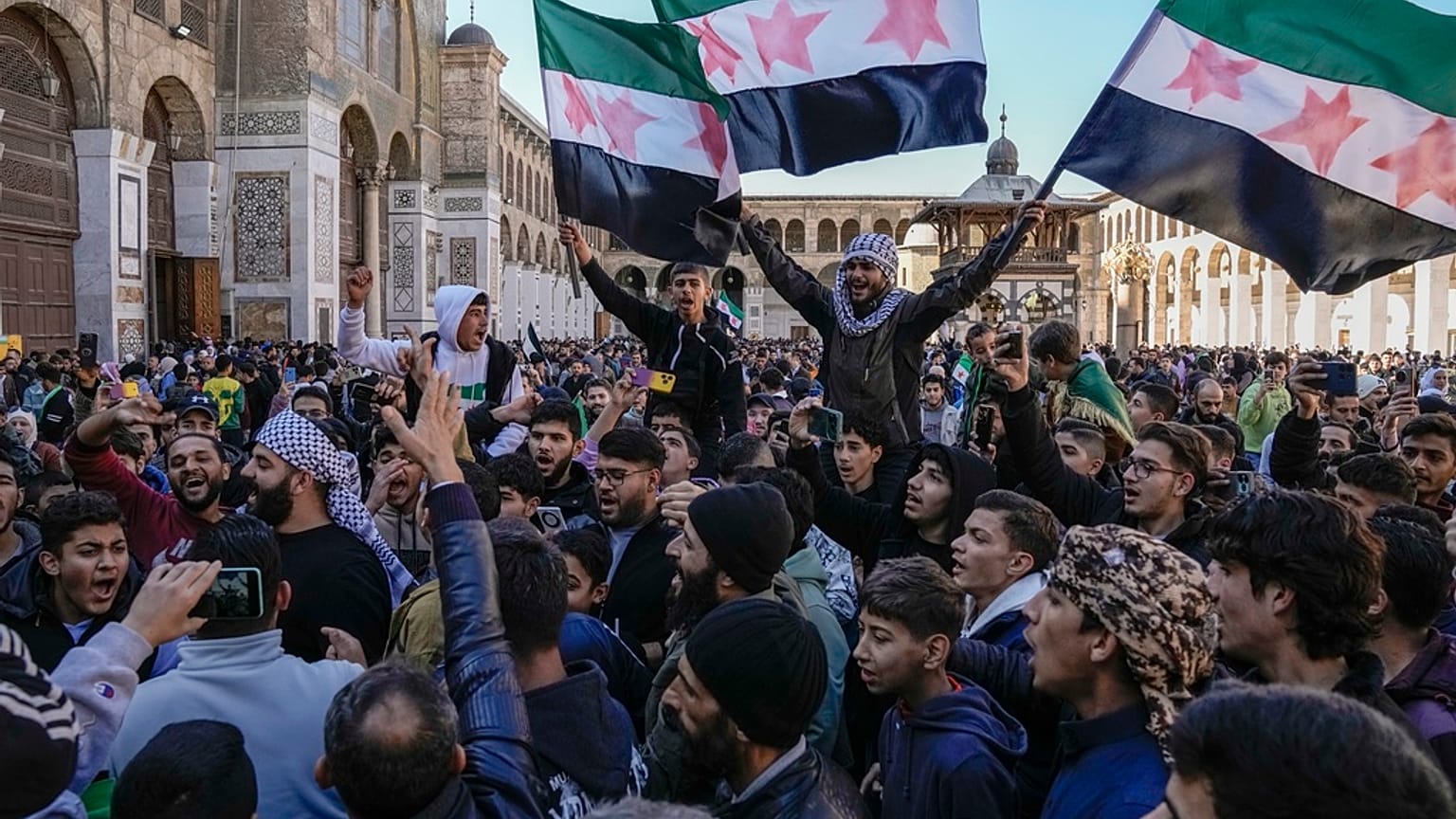 أشخاص يهتفون ويلوحون بالعلم السوري الجديد أثناء تجمعهم للصلاة يوم الجمعة في المسجد الأموي في دمشق بسوريا 13 كانون الأول ديسمبر 2024