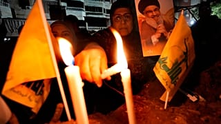 امرأة تضيء شموعًا في الموقع الذي قُتل فيه الأمين العام السابق لحزب الله حسن نصر الله بغارات إسرائيلية في الضاحية الجنوبية لبيروت، لبنان، السبت 30 نوفمبر/تشرين الثاني 2024