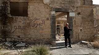 بخور شمانتوب، 74 عامًا، يقف أمام كنيس جوبر المدمر في دمشق، سوريا، وسط الحرب المستمرة.