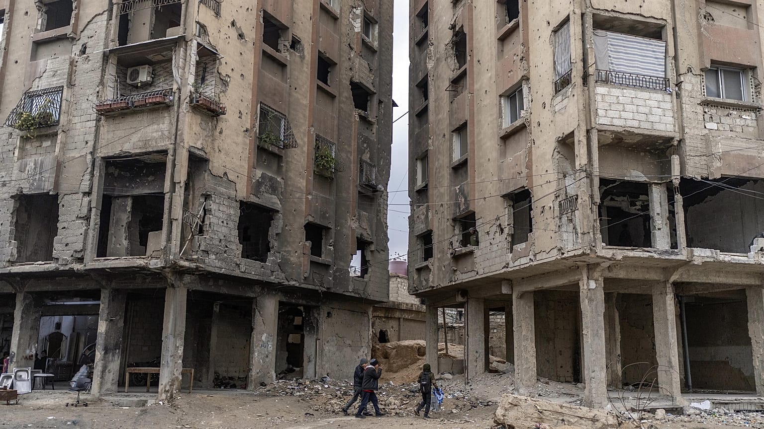 Personas caminan entre edificios dañados por ataques aéreos durante el gobierno de al-Assad en Douma, 29 de diciembre de 2024.