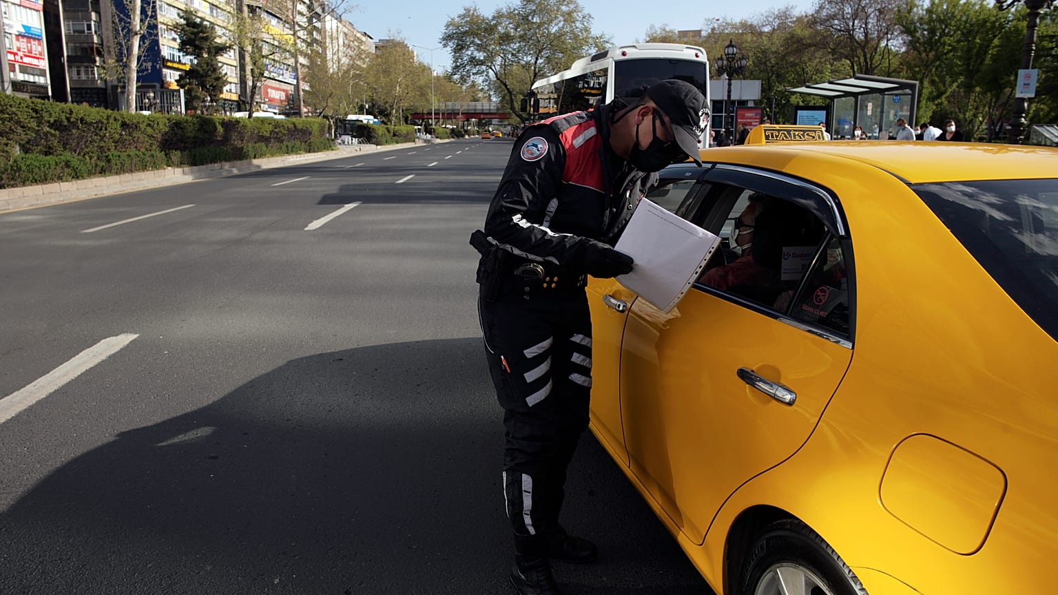 COVID-19 pandemisi sürecinde bir trafik polisi, bir taksideki kişilerin tedbirlere uyup uymadığını kontrol ediyor, 30 Nisan 2021