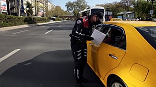 COVID-19 pandemisi sürecinde bir trafik polisi, bir taksideki kişilerin tedbirlere uyup uymadığını kontrol ediyor, 30 Nisan 2021