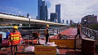 Operai a Shanghai impegnati nella costruzione di un ponte pedonale sopraelevato