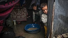 Les frères Belal, 5 ans, et Mohammed Hamad, 7 ans, récupèrent l'eau de leur tente familiale inondée après les pluies de la nuit dans le camp de tentes de réfugiés, 31 décembre 2024. 