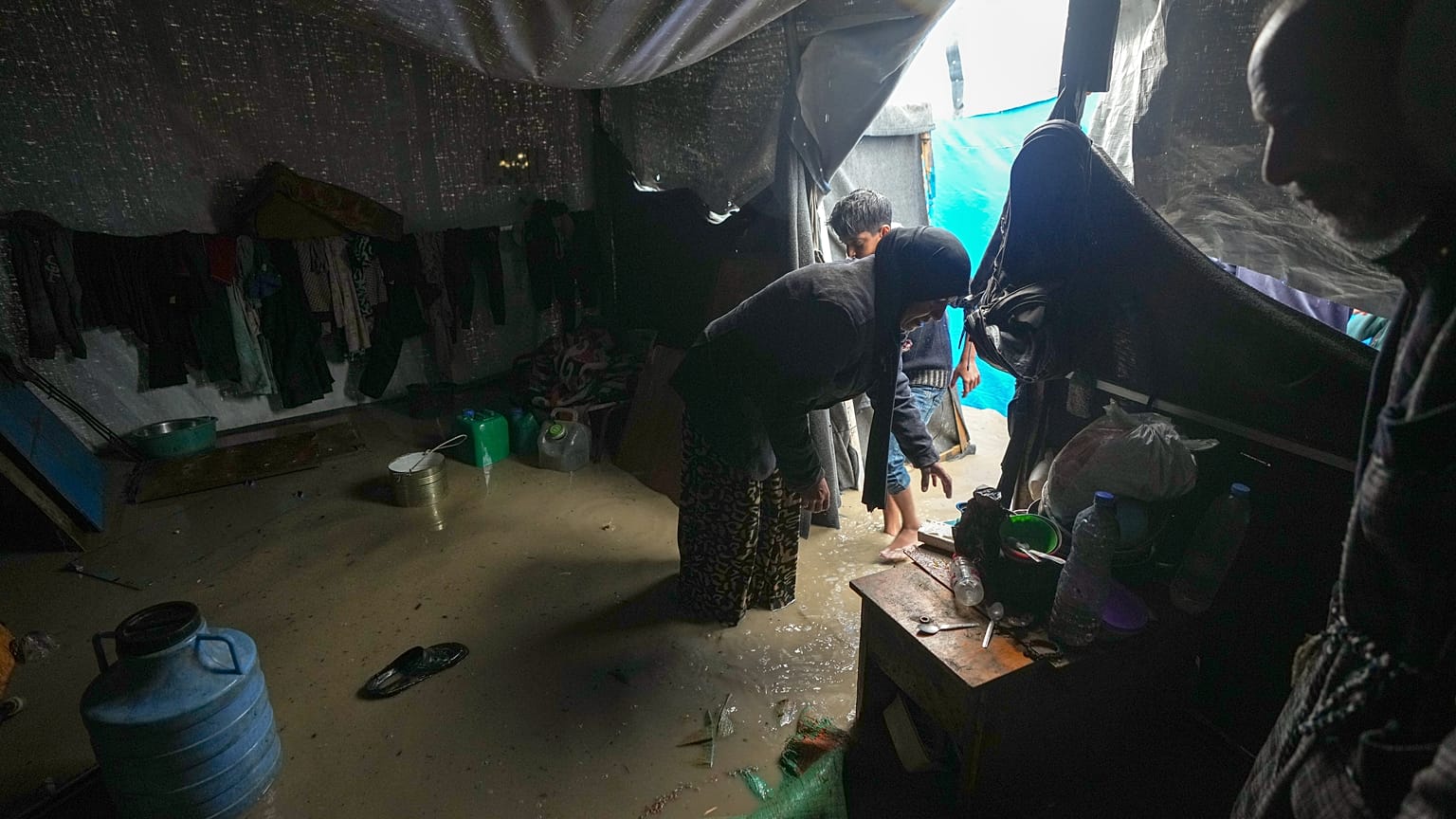منال لباد نازحة من مدينة غزة تحاول تنظيف خيمتها التي غمرتها المياه بعد هطول أمطار غزيرة في دير البلح وسط قطاع غزة، الثلاثاء 31 ديسمبر/كانون الأول 2024