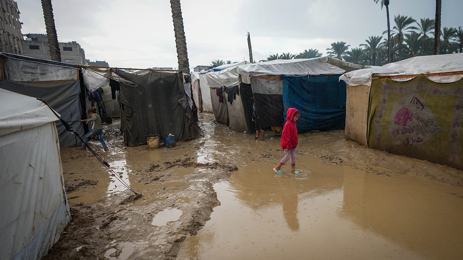 Una niña camina por una calle inundada tras las lluvias caídas durante la noche en un improvisado campo de refugiados en el centro de la Franja de Gaza.
