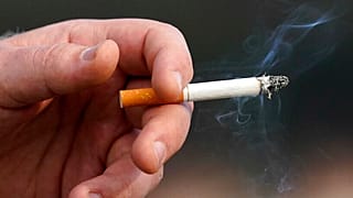 Un hombre sostiene un cigarrillo encendido mientras