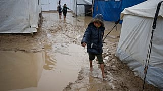Deyr El Balah'taki bir çadır kampında, bir çocuğun yalın ayak çamurun içinde yürüdüğü görülüyor, 31 Aralık 2024