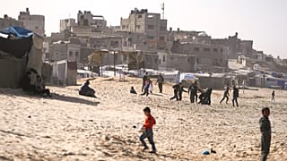 Lakóhelyükről kitelepített palesztin gyerekek játszanak a homokban a Gázai övezet középső részén fekvő Deir al-Balah tengerpartján 2024. december 27-én.