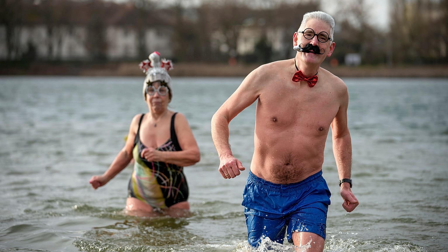 Pessoas com chapéus e bonés elegantes assistem à natação anual de Ano Novo do clube de natação de inverno "Seehunde Berlin", no dia de Ano Novo, no lago Oranke, em Berlim, a 1 de janeiro de 2025.