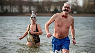 Emberek díszes kalapokban és sapkákban vesznek részt a "Seehunde Berlin" téli úszóklub éves újévi úszásán, újév napján a berlini Oranke-tónál 2025. január 1-jén.