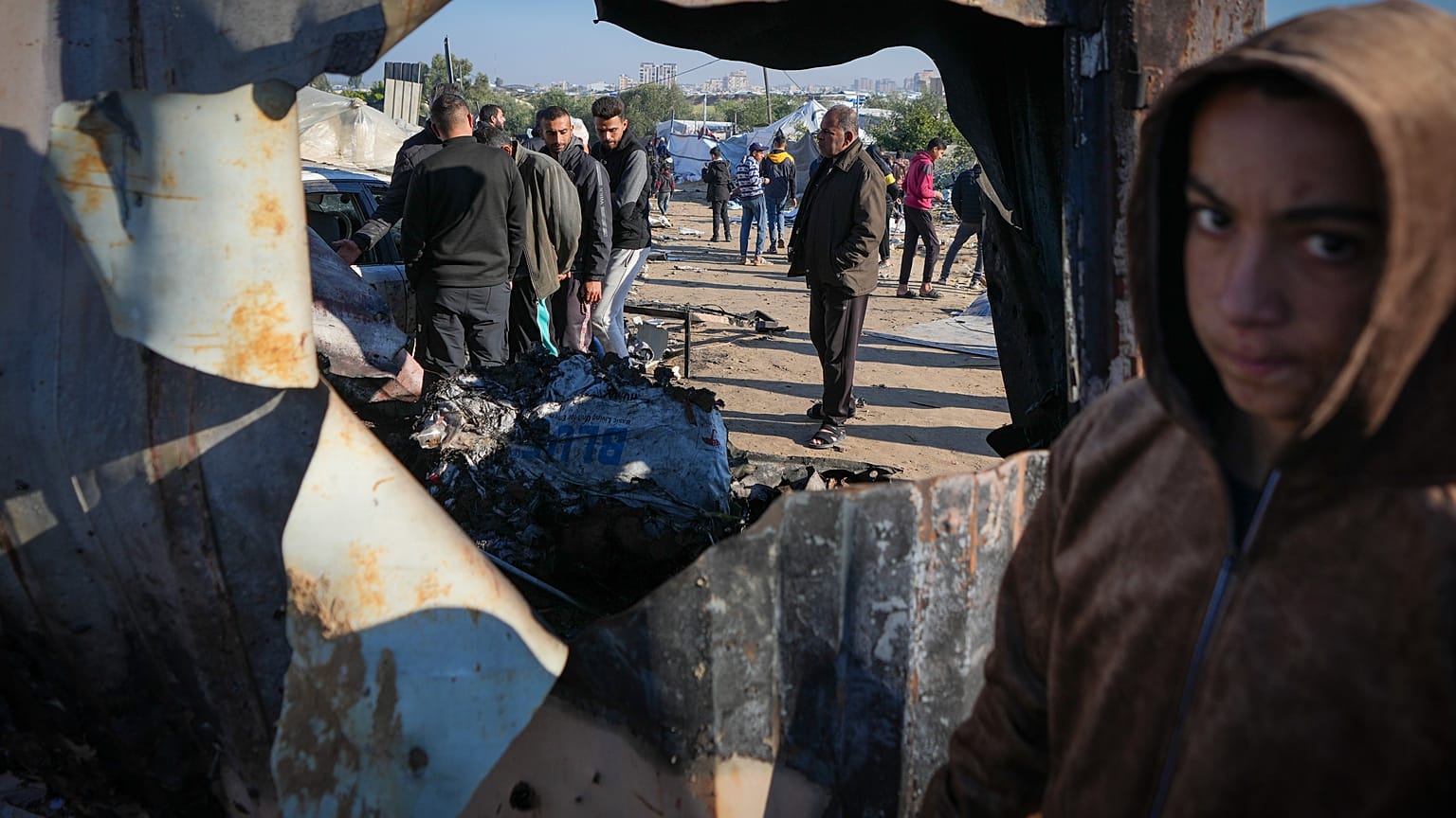 فلسطينيون يتفقدون موقع غارة للجيش الإسرائيلي في منطقة المواصي، في خان يونس، وسط قطاع غزة، الخميس 2 يناير/كانون الثاني 2025