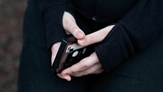 مراهقة تحمل هاتفا محمولا
