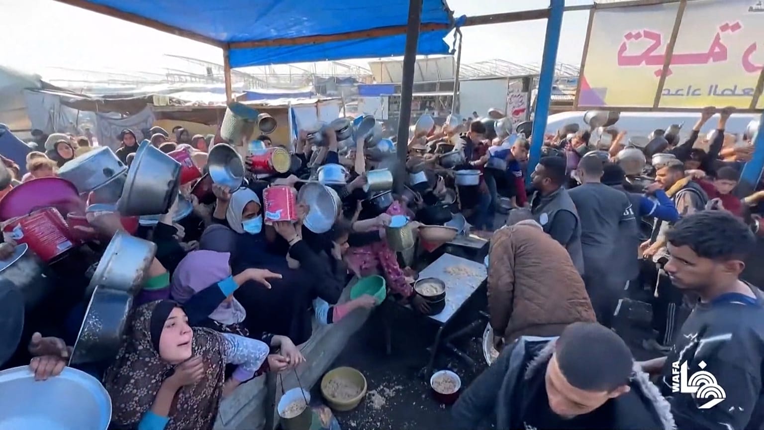Des foules agitent des casseroles au-dessus de leur tête pour obtenir de l'aide alimentaire à Khan Younis.