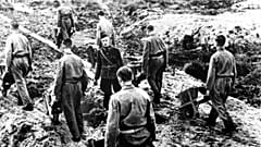 Häftlinge des niederländischen Arbeitskorps arbeiten in Kettenarbeit unter einem Nazi-Vorarbeiter in einem Zwangsarbeitslager in den Niederlanden, 2. März 1944 