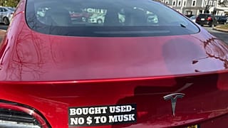 Vehículo tesla con el letrero: "Comprado usado, no dólares para Musk".