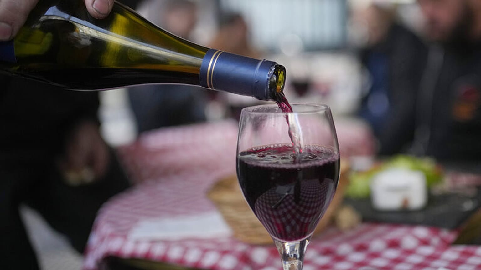 ARQUIVO: Um cliente serve um copo de vinho Beaujolais Nouveau num restaurante de Boulogne Billancourt, nos arredores de Paris, quinta-feira, 18 de novembro de 2021. 
