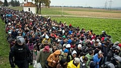 مهاجرون يمرون بجانب كنيسة صغيرة بعد عبورهم من كرواتيا، في ريغونتشي بالقرب من معبر حدودي بين كرواتيا وسلوفينيا، 22 أكتوبر 2015 