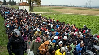 مهاجرون يمرون بجانب كنيسة صغيرة بعد عبورهم من كرواتيا، في ريغونتشي بالقرب من معبر حدودي بين كرواتيا وسلوفينيا، 22 أكتوبر 2015 