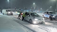 Des personnes aident à pousser des voitures coincées dans la neige à Leeds, en Angleterre, dimanche 5 janvier 2025.