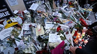 Flores y velas ante las oficinas del periódico Charlie Hebdo en París el jueves 8 de enero de 2015.