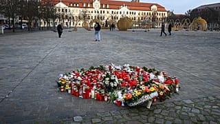 Flowers and candles are seen on a place of remembrance for the victims of the attack at Christmas market on the cathedral square with the Saxony-Anhalt parliament building. 