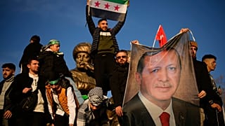 Άνθρωποι κρατούν ένα πανό του Τούρκου προέδρου Ρετζέπ Ταγίπ Ερντογάν καθώς γιορτάζουν την πτώση της συριακής κυβέρνησης στην Κωνσταντινούπολη, Τουρκία, την Κυριακή 8 Δεκεμβρίου 2024.