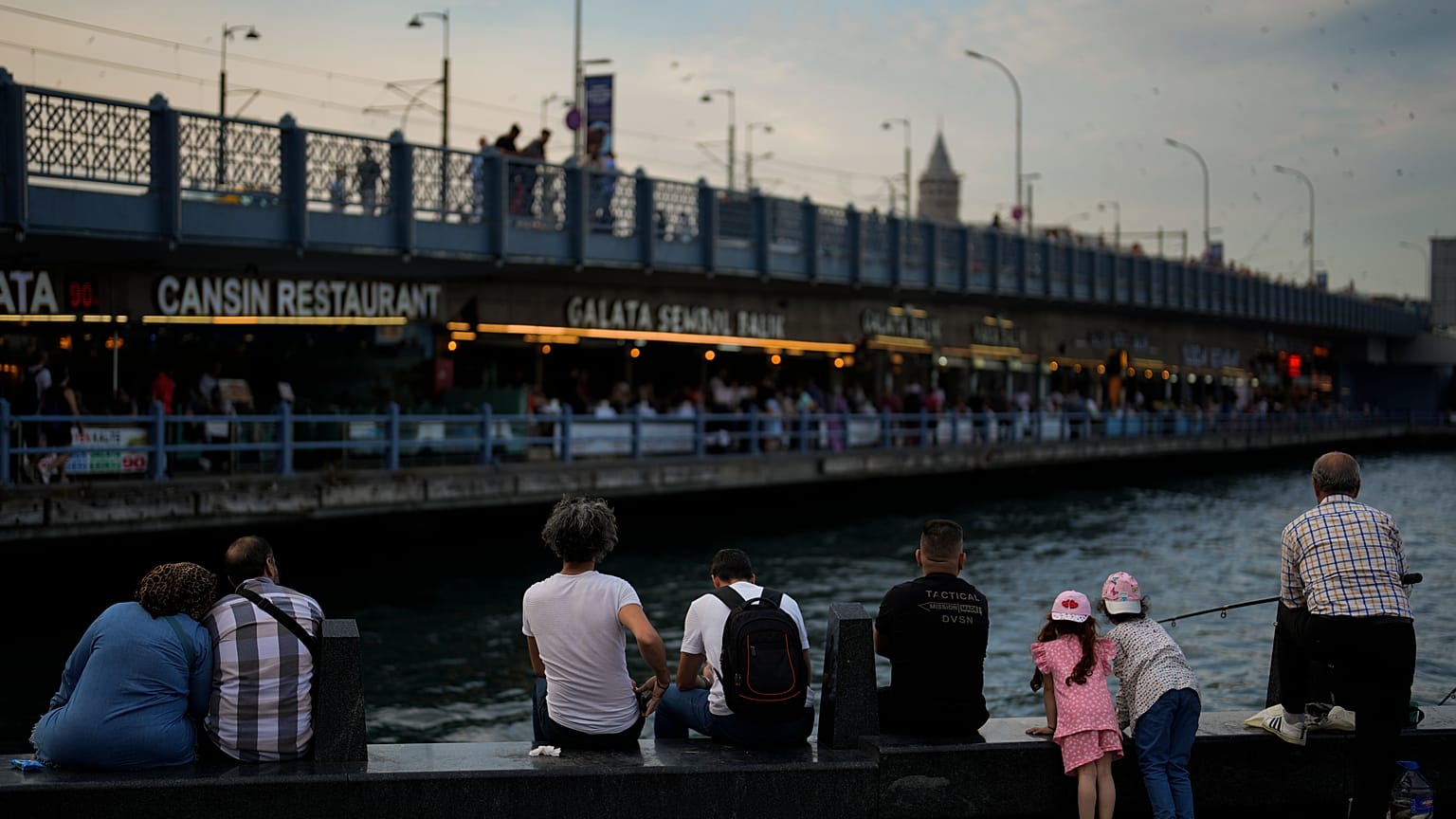 Bir grup insan İstanbul Fatih'te, Galata Köprüsü'nün kıyısında oturuyor, 20 Haziran 2023
