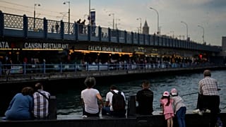 Bir grup insan İstanbul Fatih'te, Galata Köprüsü'nün kıyısında oturuyor, 20 Haziran 2023