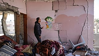 فلسطيني ينظر إلى مبنى سكني متضرر في أعقاب غارة إسرائيلية ليلية في دير البلح، قطاع غزة، الأربعاء، 8 يناير/كانون الثاني 2025