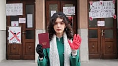 Emilija vor ihrer Universität mit einem Index-Buch und einem roten Handschuh.