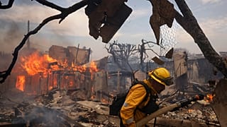 Strażak walczy z pożarem w dzielnicy Pacific Palisades w Los Angeles