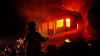 A firefighter works as the Palisades Fire burns a house in the hill next to the Getty Villa Wednesday, Jan. 8, 2025, in Pacific Palisades, Calif. 