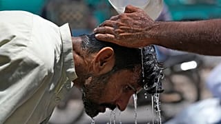 Um voluntário deita água para refrescar um homem durante um dia quente em Karachi, no Paquistão.