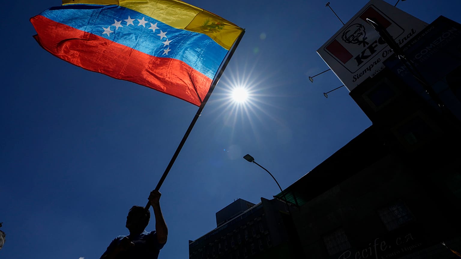 Un uomo sventola una bandiera durante una protesta degli oppositori del presidente venezuelano Nicolas Maduro alla vigilia del suo terzo mandato, a Caracas.