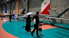 Una familia pasea delante de un dron en una exposición.