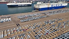 Fahrzeuge und Lastwagen für den Export warten in einem Hafen in Yantai in der ostchinesischen Provinz Shandong auf ihren Transport