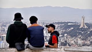 Residents talk, with the monument to the Martyrs in background, right, Monday, Jan. 6, 2025 in Algiers. 