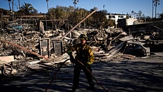 Tűzoltó egy leégett ház romjai előtt Los Angeles közelében