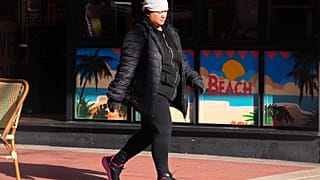 Una mujer camina visiblemente abrigada
