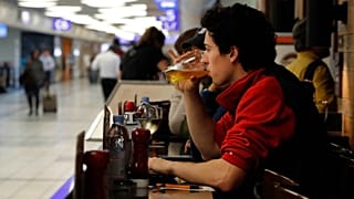 Un passeggero sorseggia una birra in attesa di imbarcarsi su un volo all'aeroporto internazionale Lambert di St. Louis.