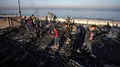 فلسطينيون يفحصون موقع ضربة جوية للجيش الإسرائيلي في دير البلح، وسط قطاع غزة، صباح الثلاثاء، 14 يناير 2025.