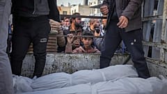 طفل ينظر إلى جثث فلسطينيين قتلوا في القصف الإسرائيلي على قطاع غزة أثناء نقلها للدفن في مستشفى الأقصى في دير البلح 15 كانون الثاني يناير 2025
